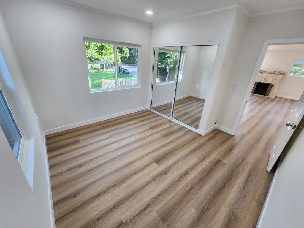 Finished room with wood-look flooring and mirrored closet doors