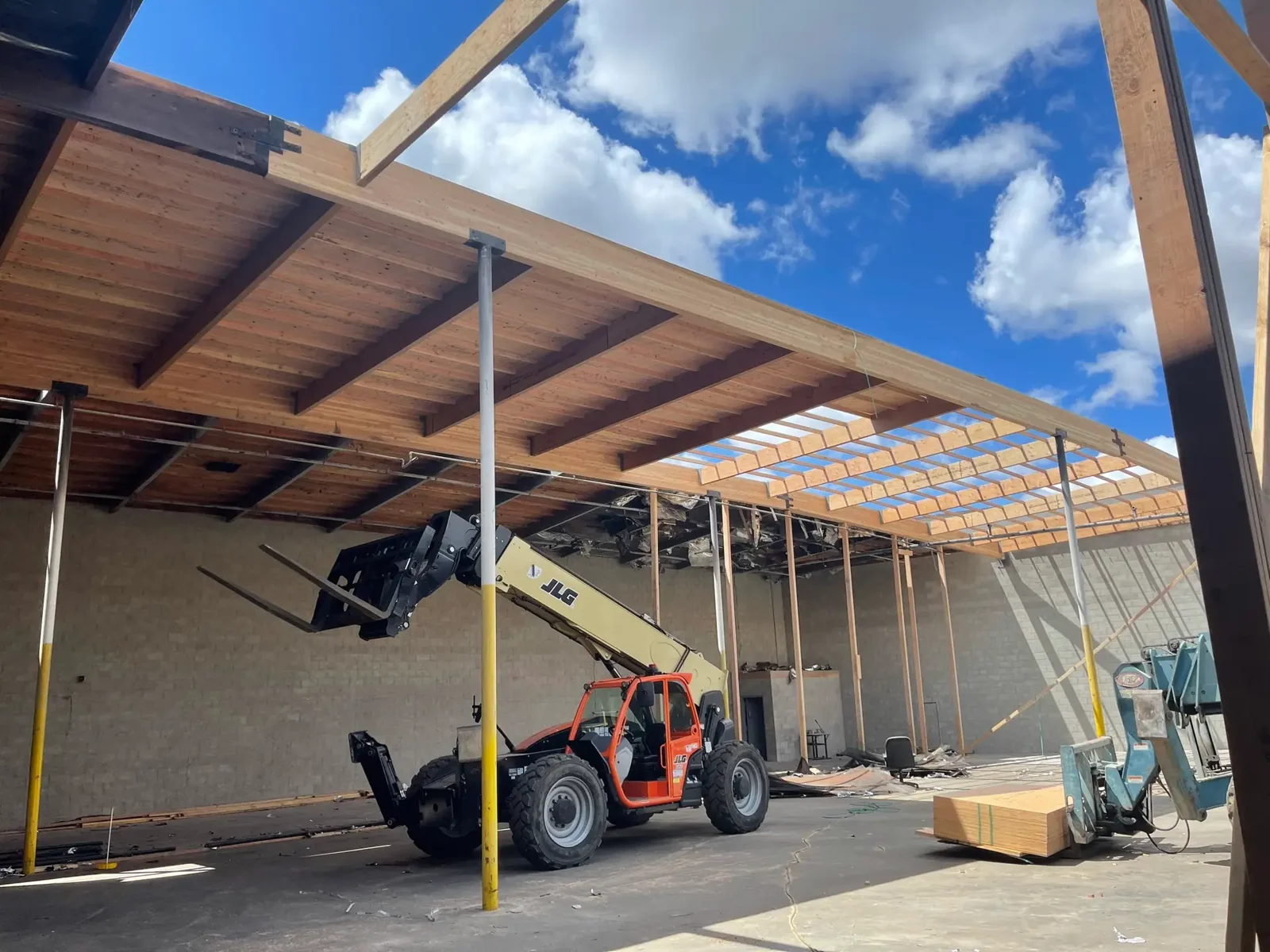 Commercial construction site with exposed roof framing and lift equipment