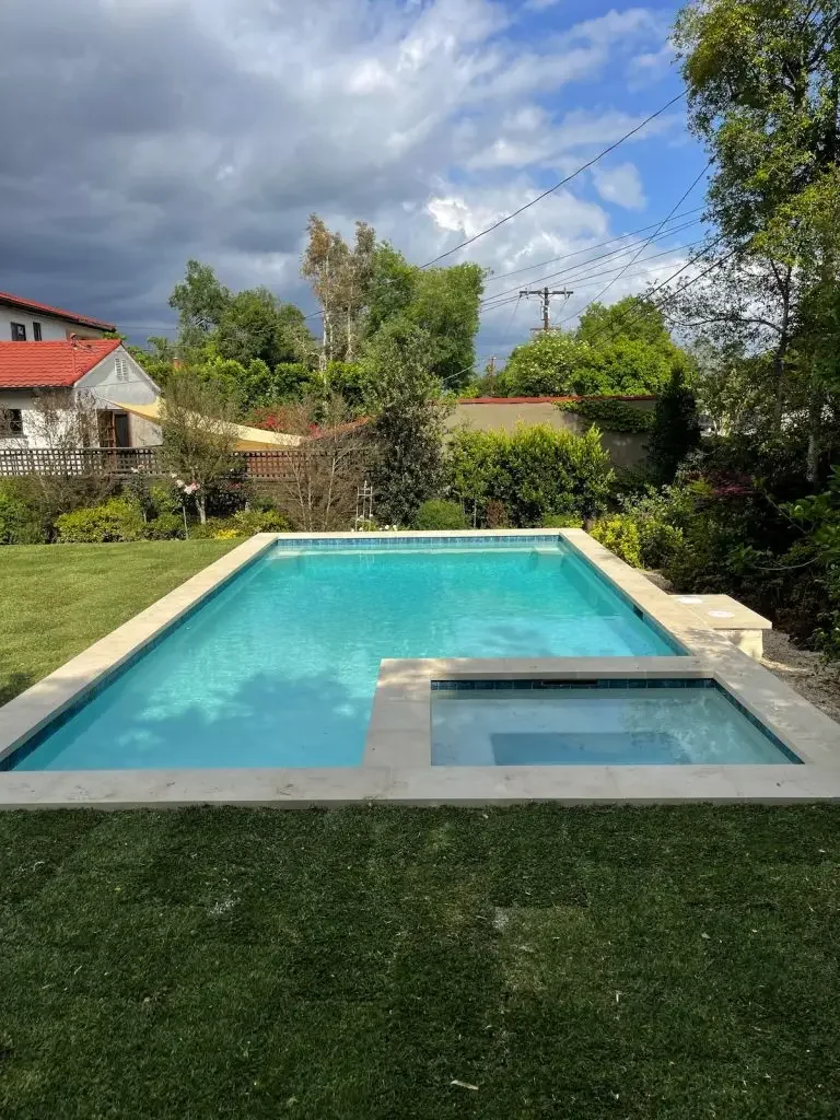 Long backyard pool with an adjoining spa and landscaping
