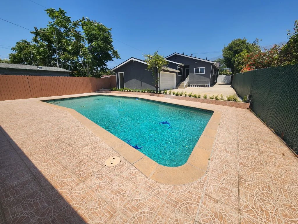 Backyard swimming pool surrounded by a paved patio